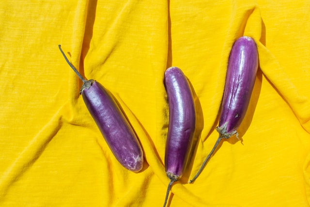 3 purple aubergines on yellow sheet
