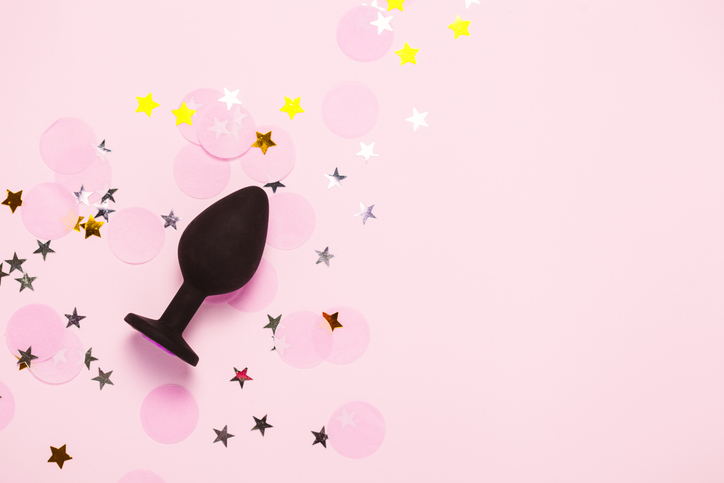 Adult sexy toy anal plug on pink background with confetti