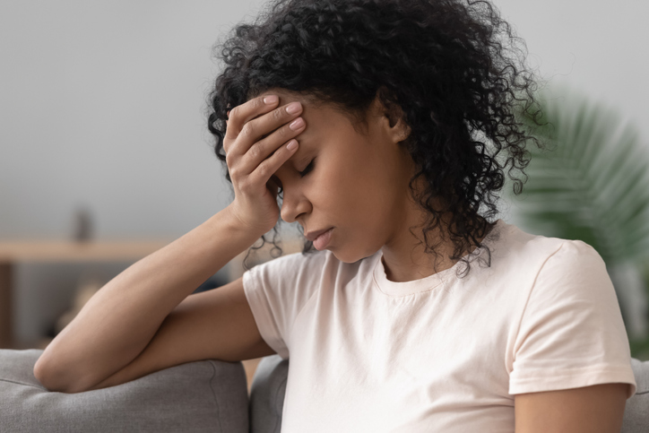 Woman sitting on couch with headache