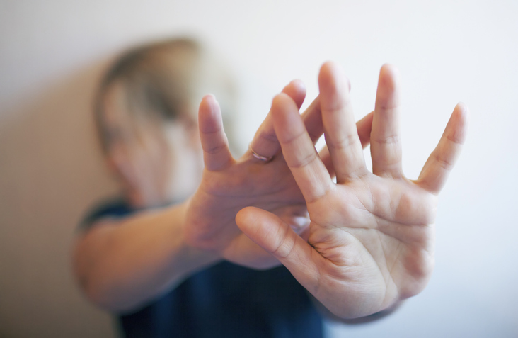 Blurred face of a woman with her arms stretched in front of her to protect herself