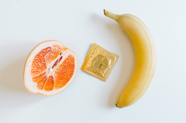Condom between orange and banana