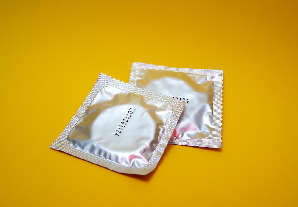2 condoms on yellow background STI STD protection