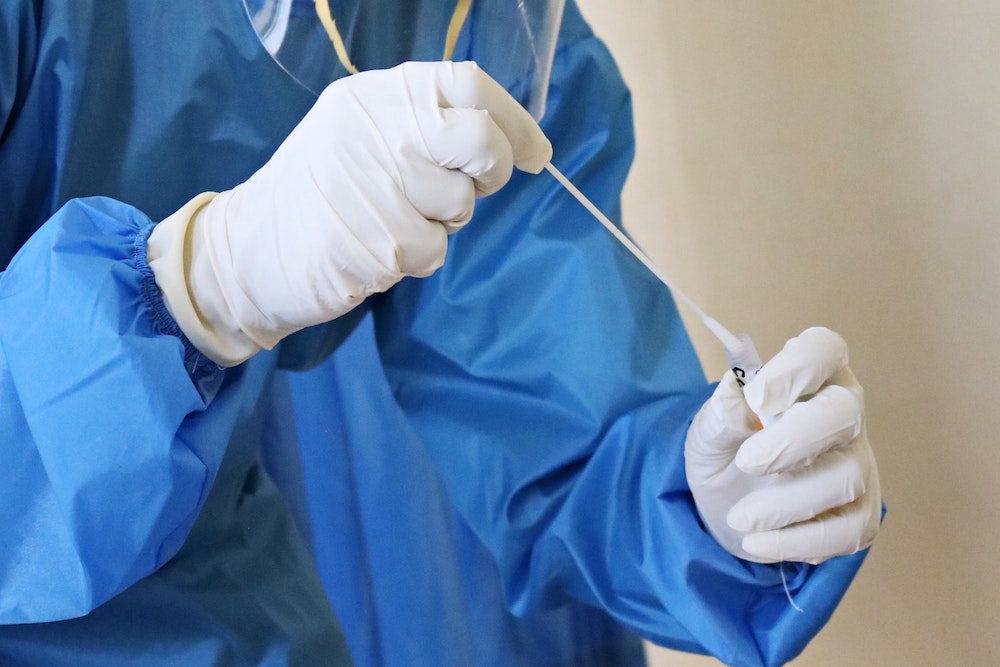 Person in PPE handling COVID-19 test swab