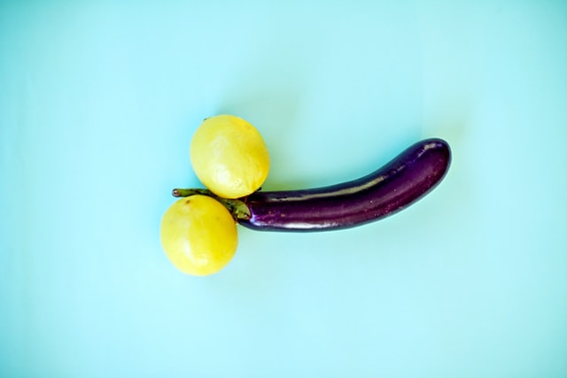 Two lemons either side of an aubergine on a blue background