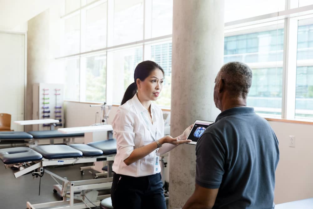 Doctor explaining cerebrovascular disease diagnosis to patient on iPad
