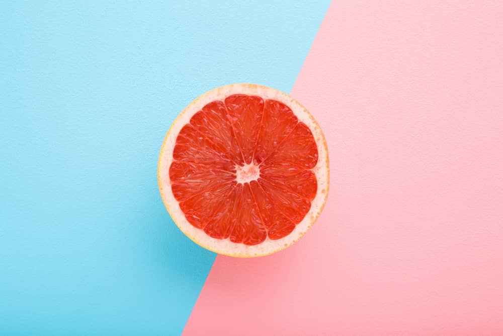 Half a grapefruit on pink and blue background for female masturbation