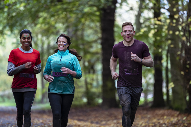 Group of friends laughing and running through woods