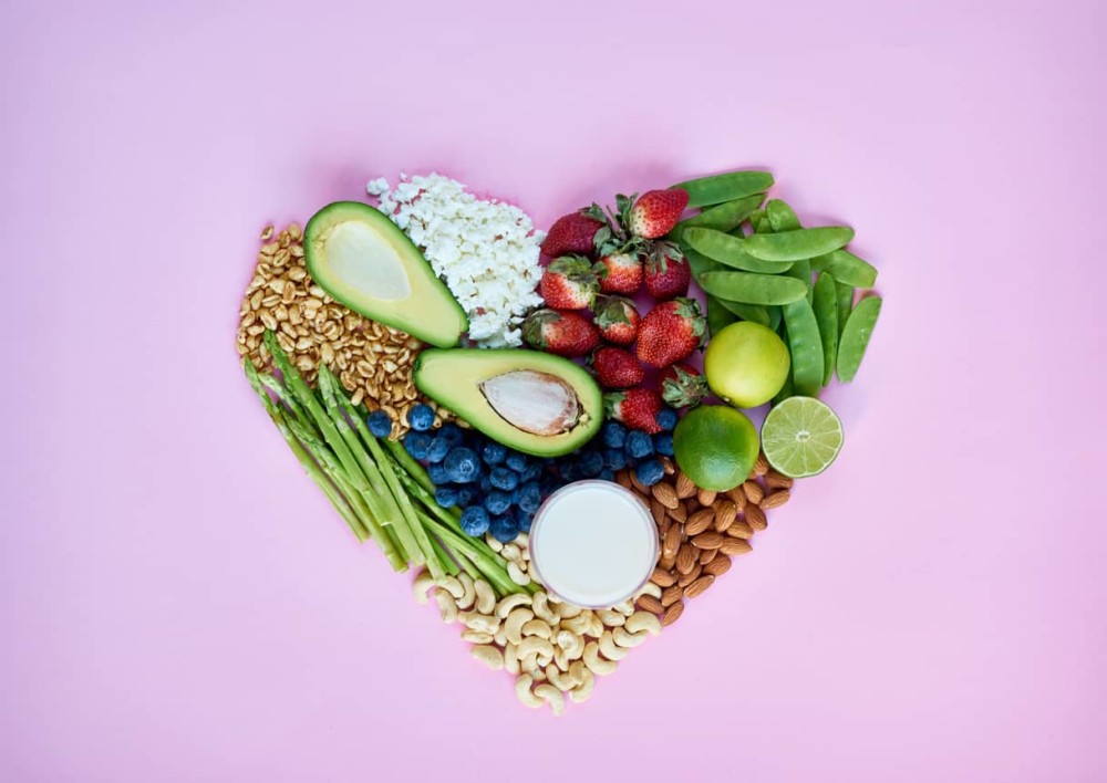 heart healthy foods to eat arranged in heart shape on pink background