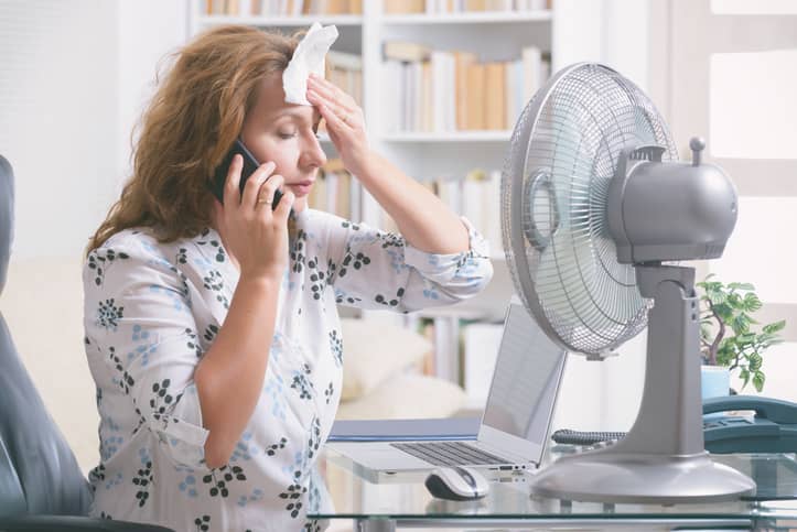 Woman having a hot flush at her office desk