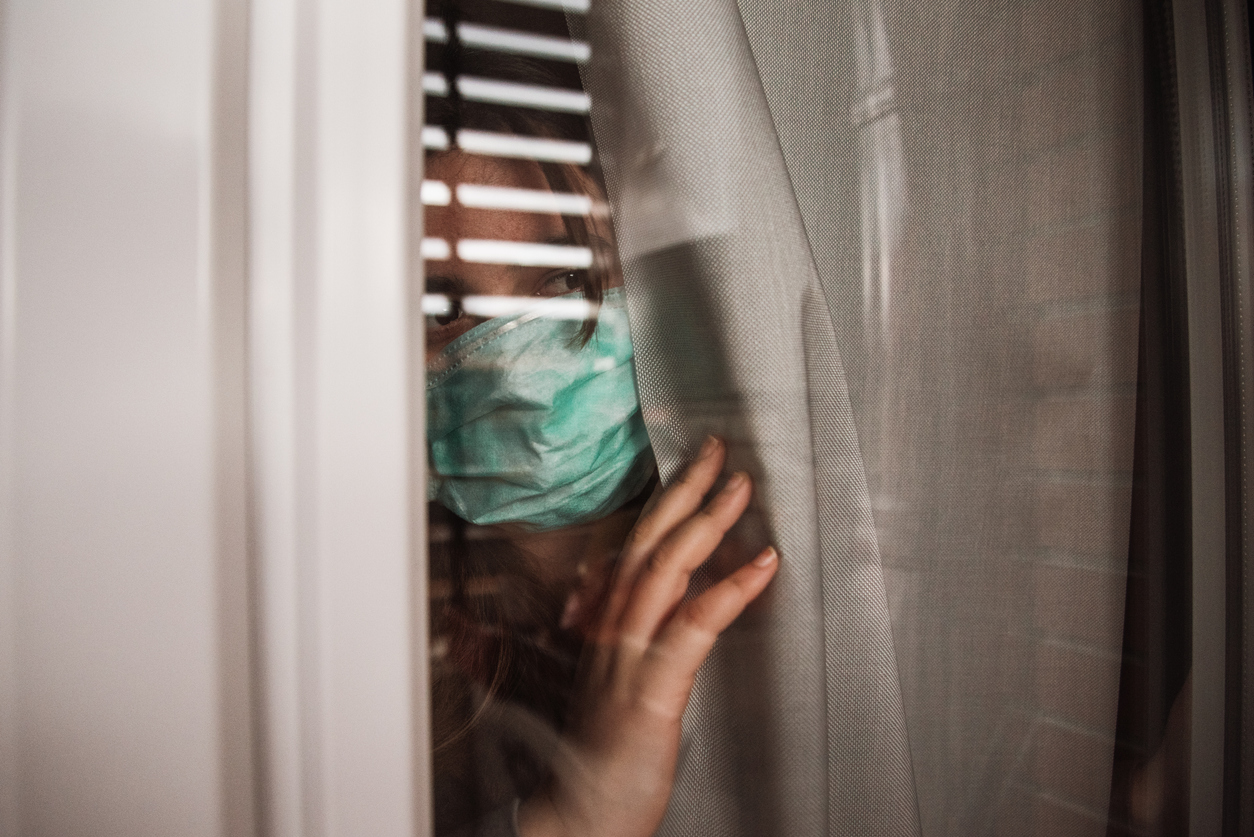 woman-looking-out-of-window-with-surgical-mask