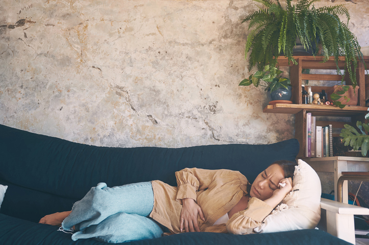 woman on sofa stomach pain 