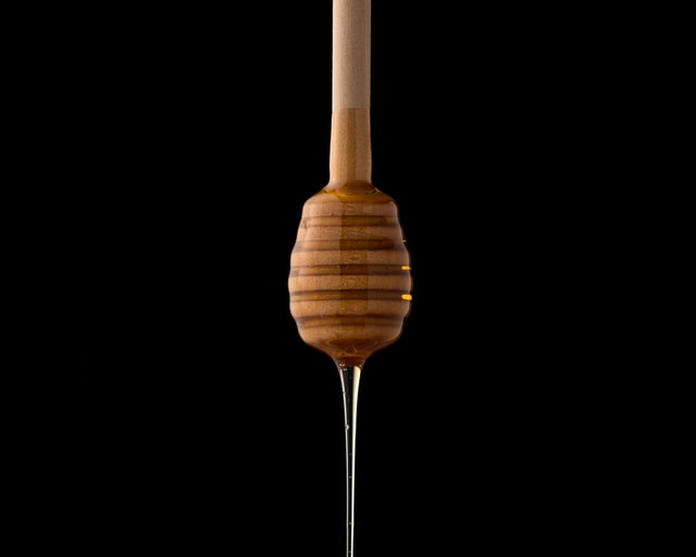 Honey running from a wooden dipper