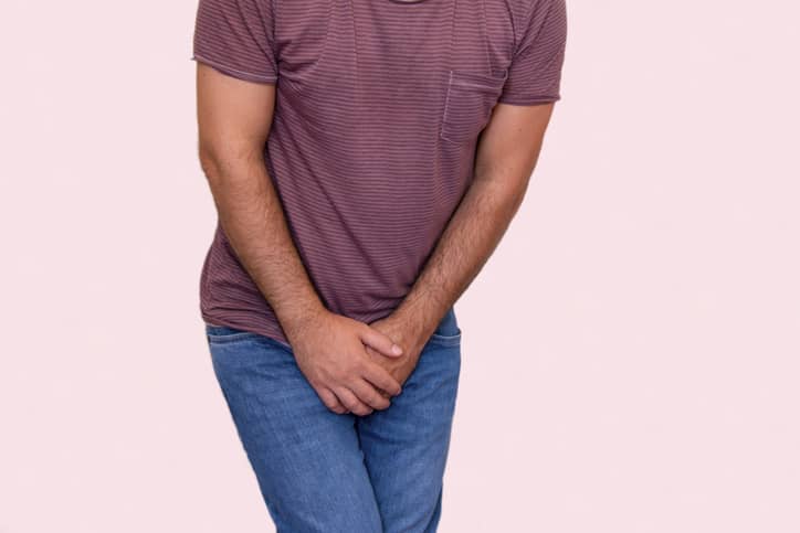 Man holding his hands over sore penis