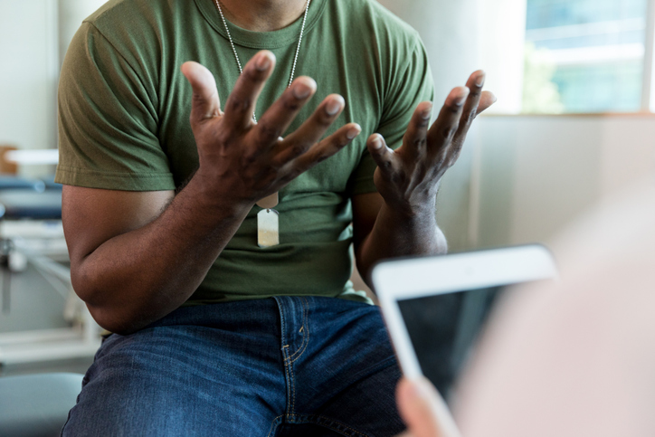 Man in green t-shirt talking to a doctor or therapist