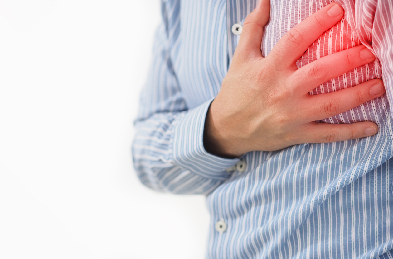 Man in striped shirt with hand on his chest, in pain