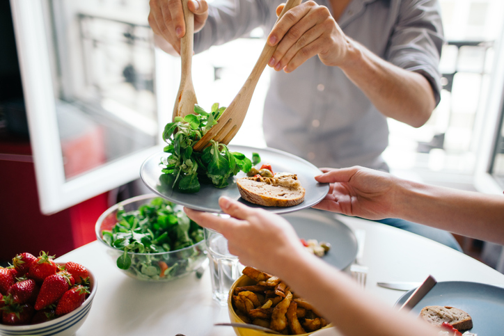 Man serving a portion of salad to someone at lunch