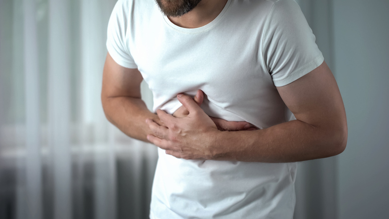 Man with hand on stomach, looking in pain