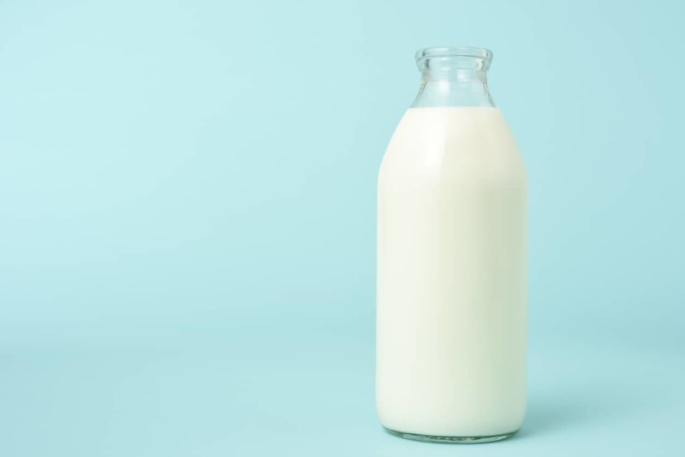 Open bottle of fresh milk on blue background