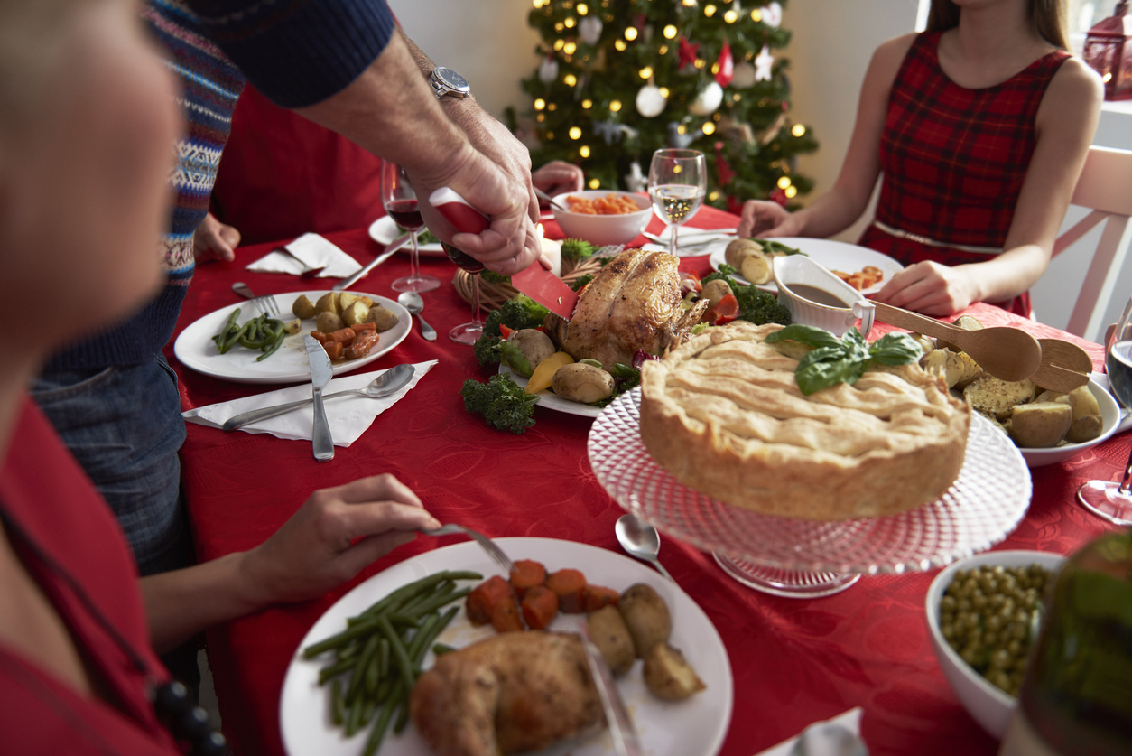 People sitting around a festive table eating food (credit - gpointstudio)