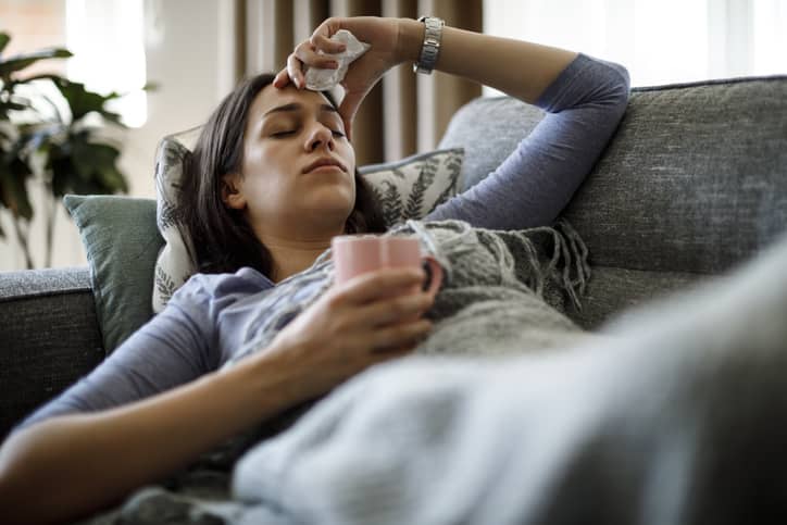 Person lying on the couch looking ill with a fever due to typhoid