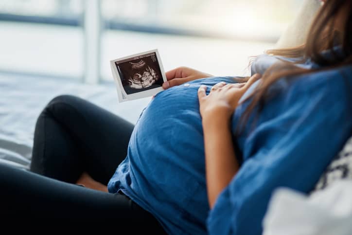 Woman on the sofa cradling her pregnant belly
