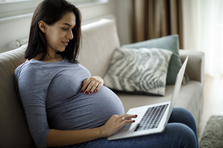 Pregnant woman using laptop on the sofa at home