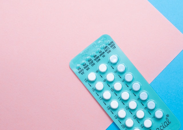 Sheet of contraceptive pills on a pink and blue background