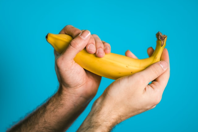 Person holding a banana on a blue background