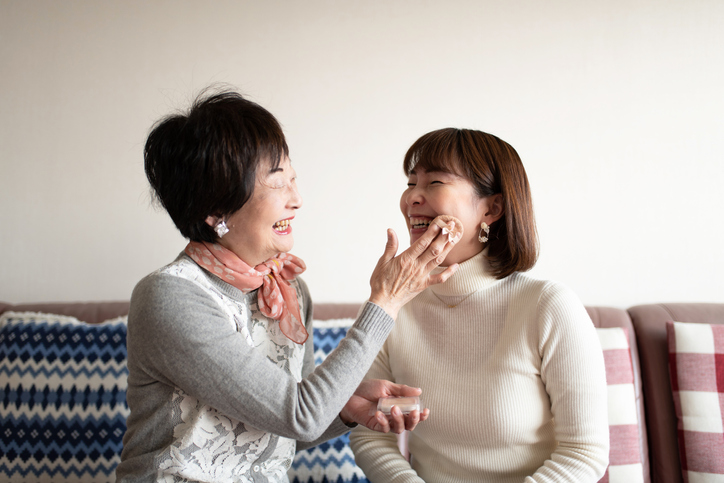 Senior woman making up at home with mid-adult woman 
