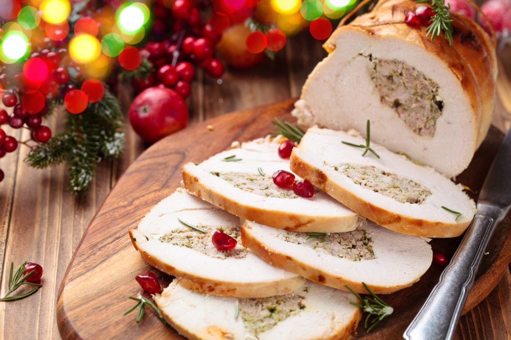 Stuffed turkey breast with pomegranate and rosemary on cutting board (credit - Vitalina)