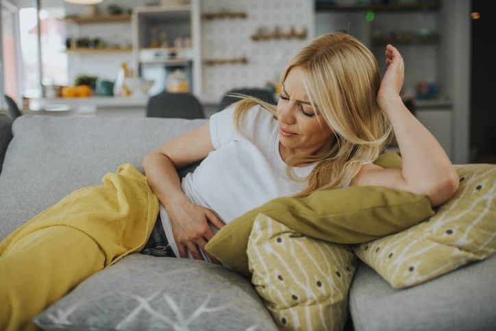 Woman holding her tummy with menopause lower abdominal pain