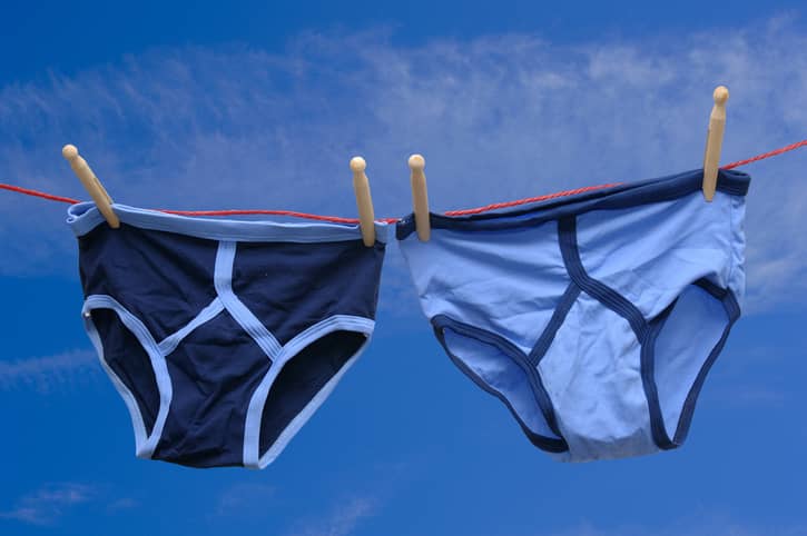 Two pairs of blue male underpants drying on a washing line