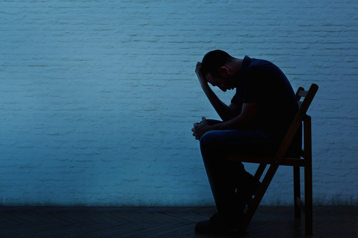Unhappy and lonely young man in front of a wall