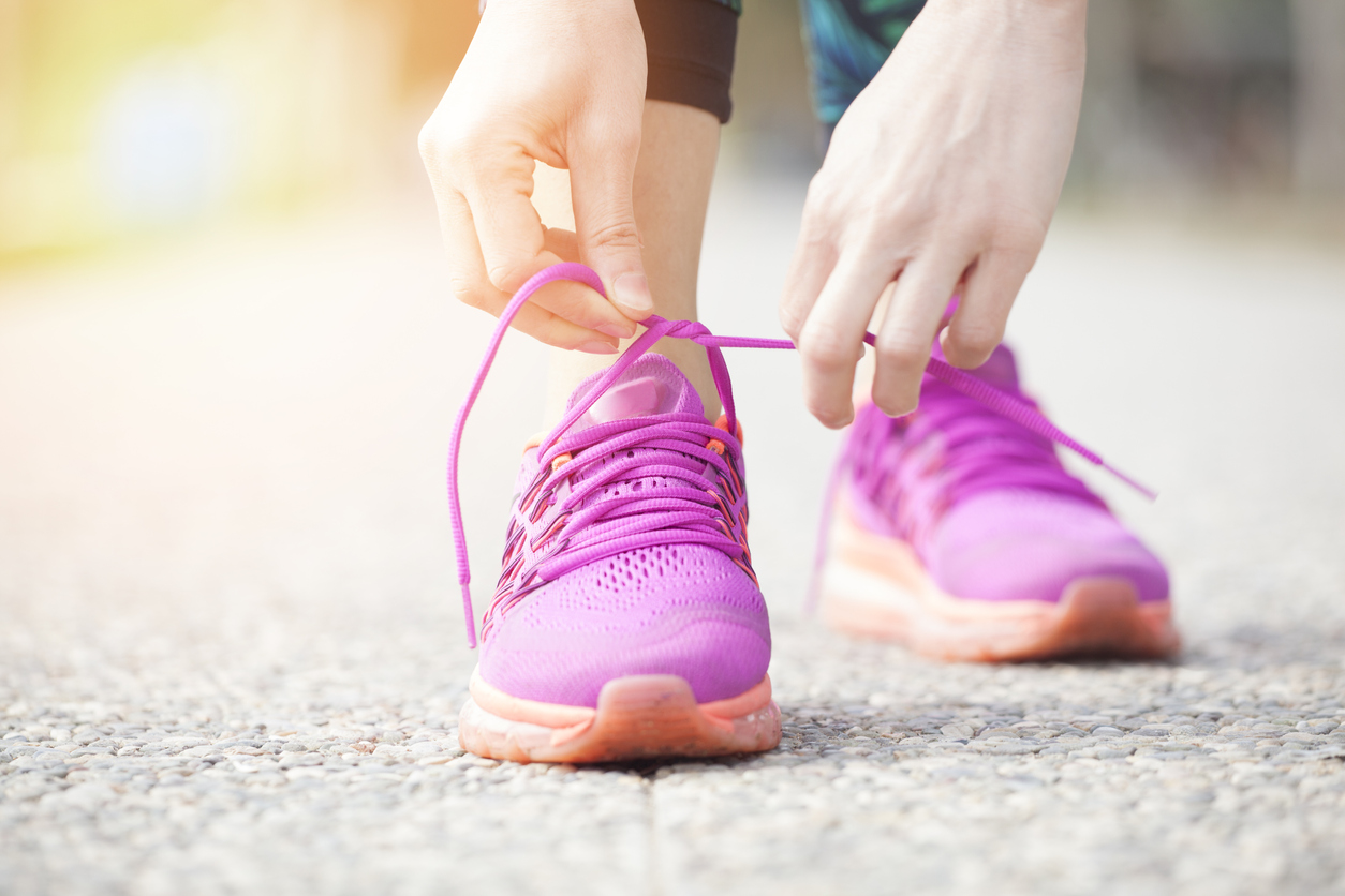 Woman putting on pink trainers and tying laces