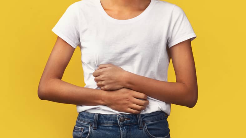 Woman holding hands on stomach suffering from abdominal pain