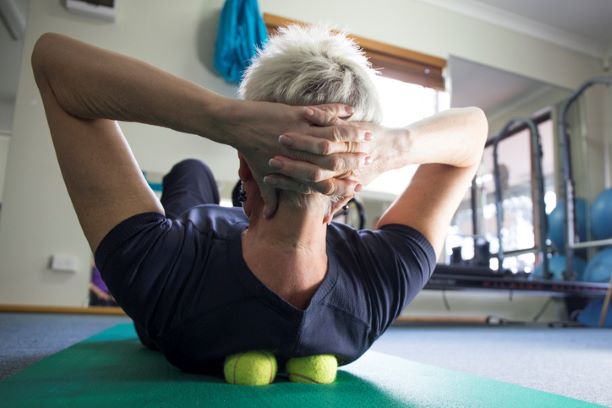 Woman practicing self-massage technique with tennis ball for back pain