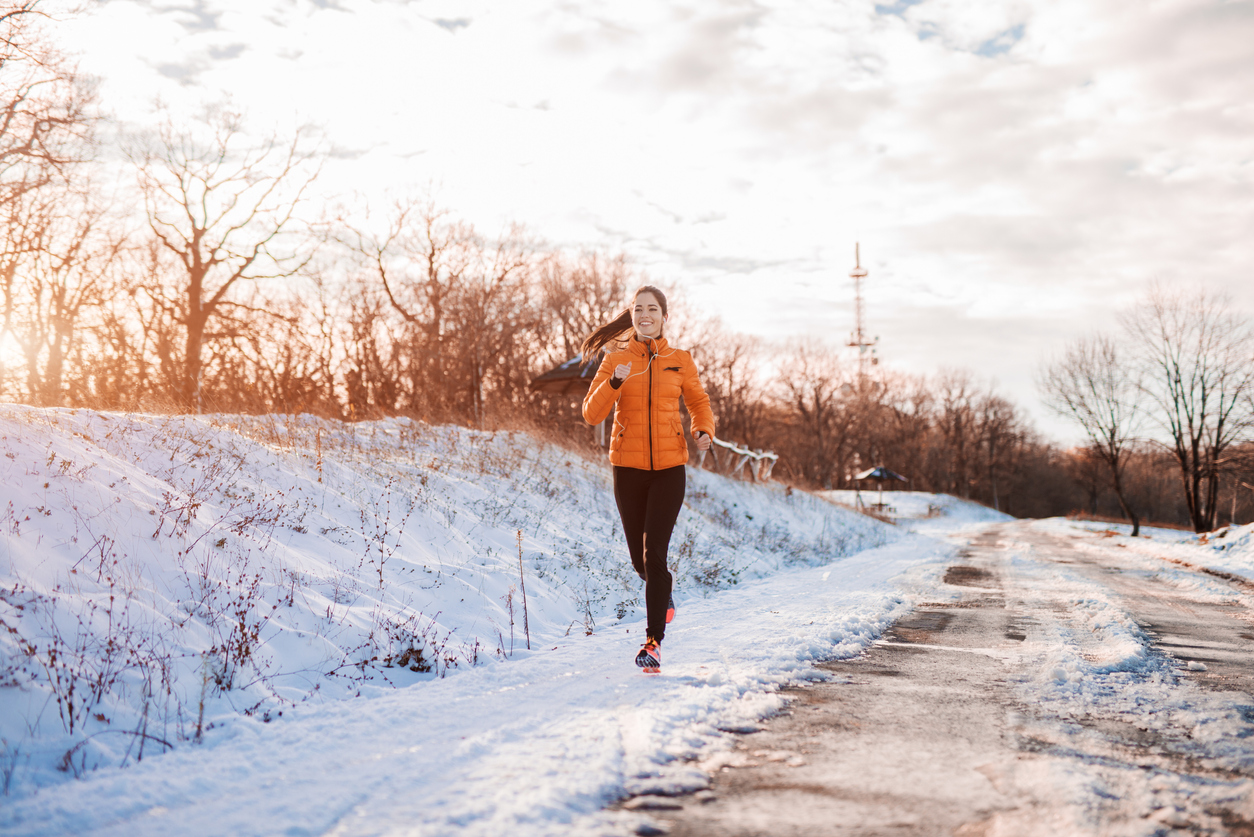Woman running outdoors along snowy track 