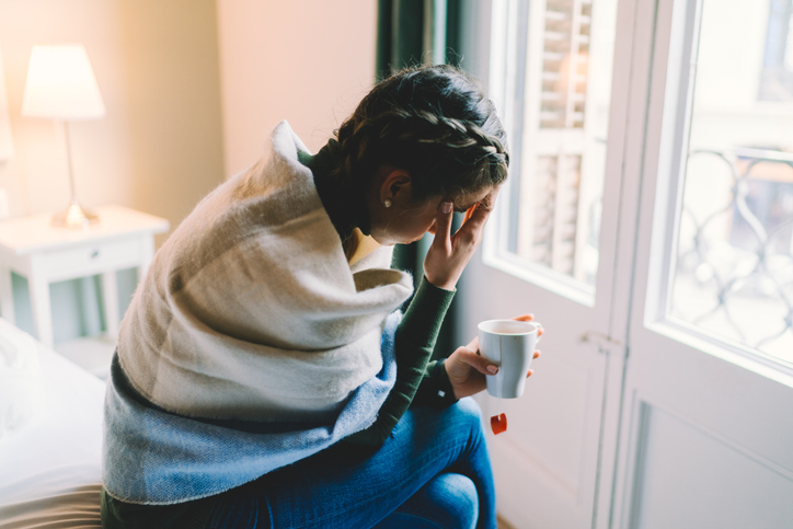 Woman sitting on bed looking anxious
