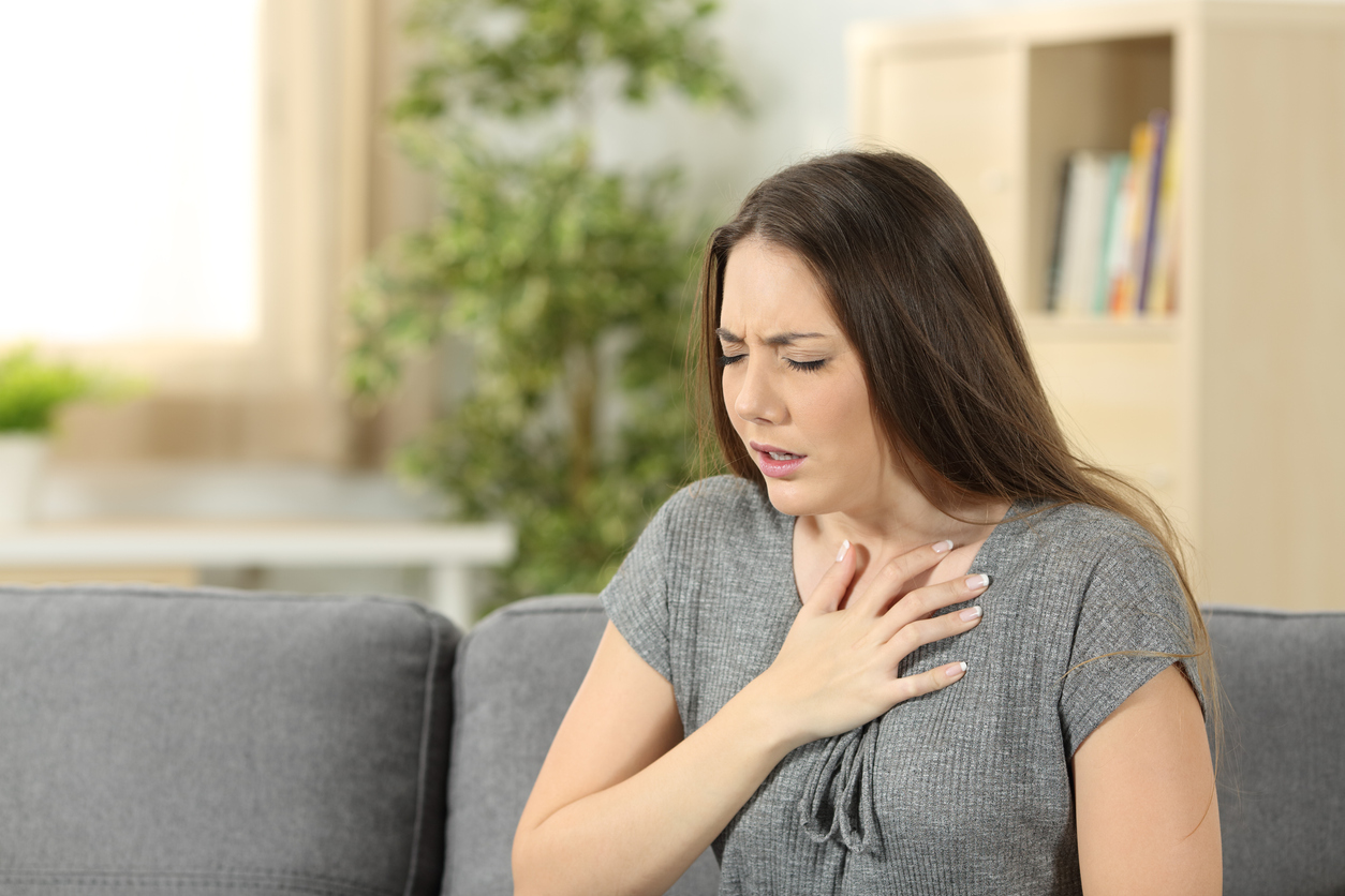 Woman with breathing problems sitting on a couch in the living room at home (Credit - AntonioGuillem)