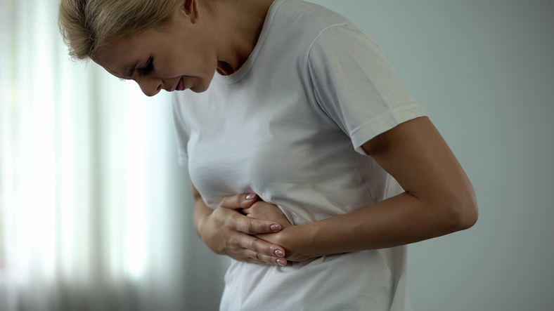 Woman with hand on her tummy and looking in pain