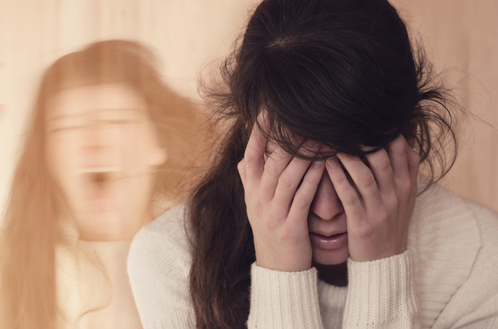 Woman with her hands over her eyes looking distressed