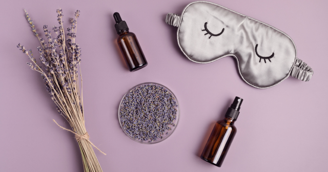 Lavendar leaves and essential oil bottles next to eye mask, natural sleep aids