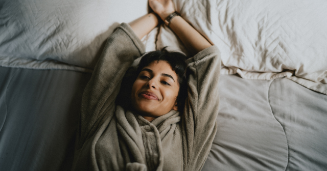 Woman lying in bed in dressing gown about to go to sleep